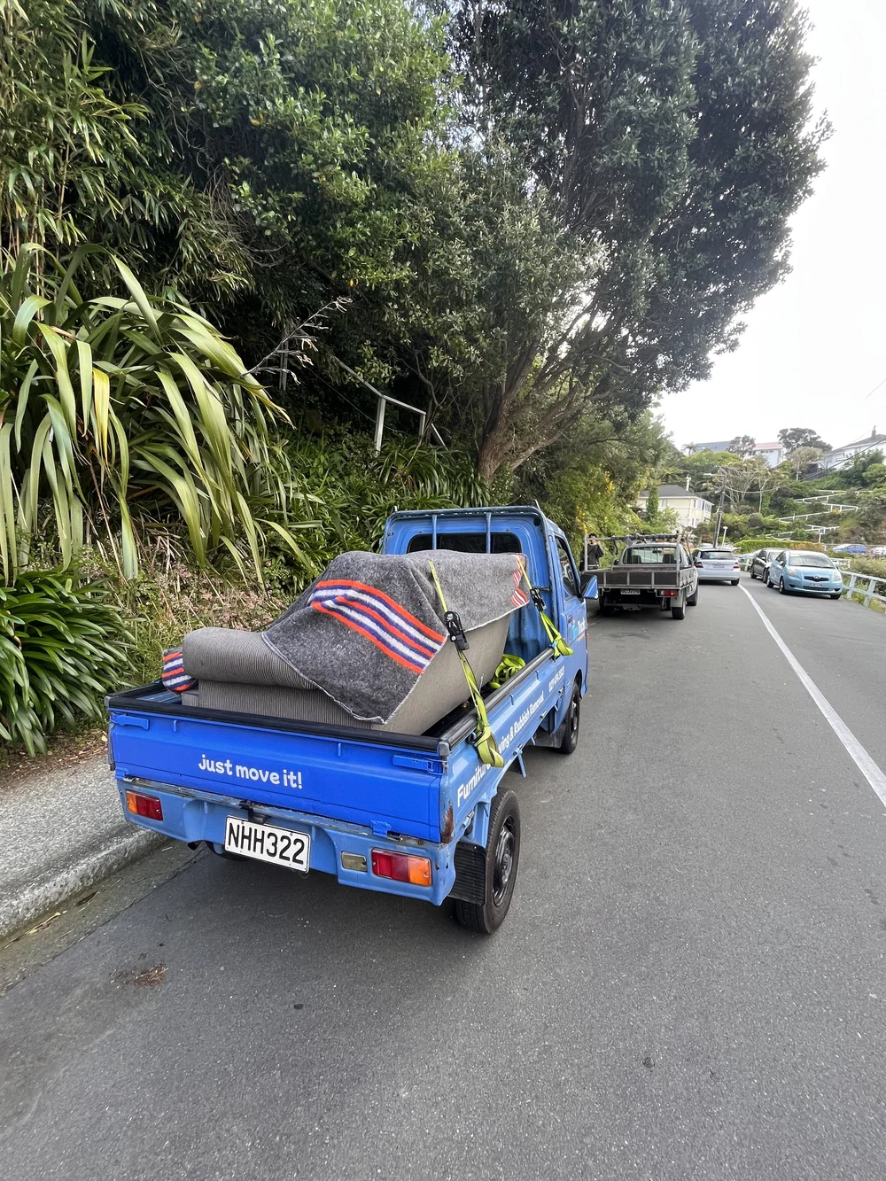 Tiny Truck on a leafy hillside street with an armchair wrapped in moving blankets