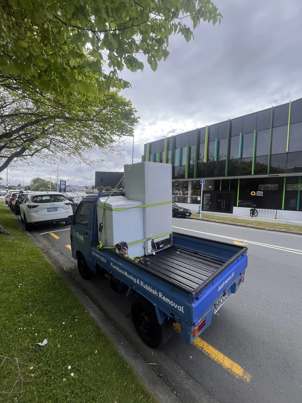 Tiny Truck carrying a fridge and a chest freezer strapped upright for an appliance move