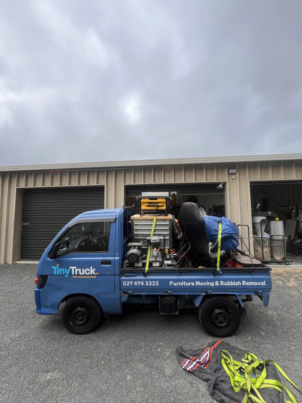 Tiny Truck loaded with a tool chest, air compressor and workshop gear outside storage units